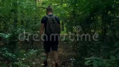 一个背着背包的留着胡子的人穿过一片<strong>茂密</strong>的<strong>森林</strong>，出现在一片<strong>森林</strong>的空地上。 摄像机跟着他移动。 自然。 乔：